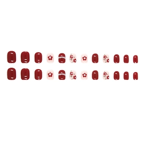 Short round red and white press-on nails with floral patterns and pearl accents