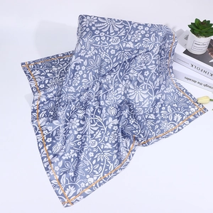 Detail of blue cashew floral silk scarf with orange border on lifestyle background