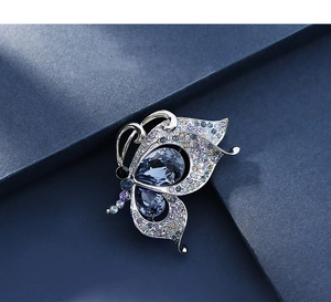 Macro shot of silver butterfly brooch with blue crystals and purple rhinestones