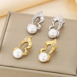 Close-up of gold and silver heart-shaped pearl earrings with crystal accents on silk