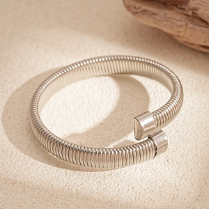 Detailed macro view of silver snake-shaped spring coil bracelet on a textured stone surface