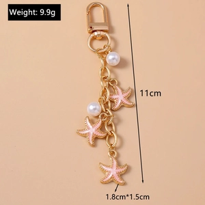 Detail of pink starfish charms and pearls on a gold keychain with dimensions