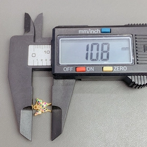 Macro view of crystal butterfly pendant being measured with digital calipers showing 10.8mm