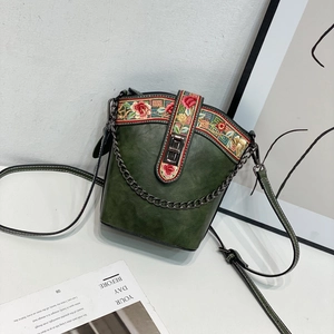 Detail of green bucket bag with floral embroidery and gold metal chain strap