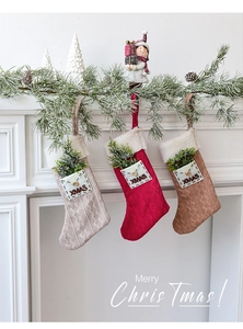 Detailed cable knit Christmas stockings with XMAS pockets hung on a festive fireplace mantel