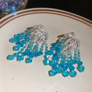 Detailed macro view of silver tassel earrings with light blue multifaceted crystal beads