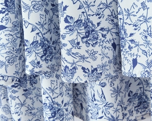 Close-up of woven fabric featuring blue and white floral porcelain patterns and pleated hem