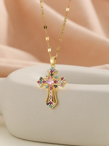 Macro detail of gold cross pendant with multi-color cubic zirconia and pink centerpiece