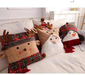 Three Christmas plush pillows featuring Santa, Reindeer, and Snowman on a soft sofa