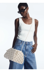 Detail shot of a beige woven leather crossbody bag showcasing premium texture and craftsmanship