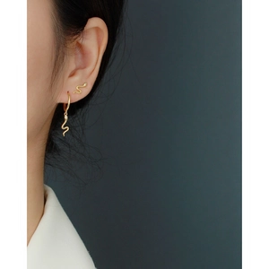 Close-up of golden S925 silver snake stud earrings with crystal inlay on a model ear