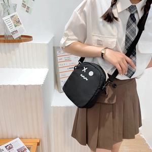 Détail du sac à bandoulière en nylon noir avec visage de dessin animé et sangle réglable