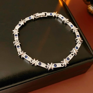 Dettaglio macro del bracciale in argento con zirconi blu e bianchi e motivi a forma di X