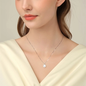 Detail of round white freshwater pearl pendant on fine silver chain worn by a model