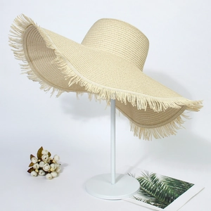 Close-up of beige summer straw hat featuring intricate woven texture and frayed edge design