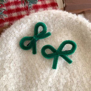 Close-up of green fuzzy bow hair clips set on a winter-themed background texture