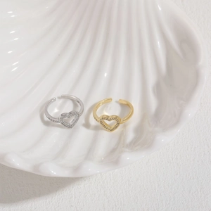 Detail of gold and silver heart-shaped adjustable rings with shimmering zircon inlay