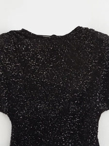 Détail des paillettes noires étincelantes et des bretelles dos nu de cette robe de fête