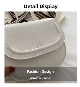 Detail of white saddle bag with red and green striped woven strap and gold buckle