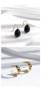 Detail of black teardrop earrings and gold C-shaped hoops with star patterns
