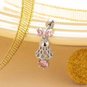Bowknot bell stud earrings with pink heart crystal in titanium steel on beige tray