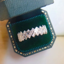 Detailed close-up of a silver ring featuring baguette and round cut stones in a velvet box