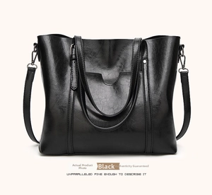 Detail of black leather bucket bag with soft gloss finish and adjustable shoulder strap