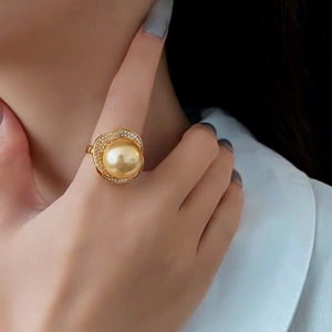 Luxurious gold ring with a large golden pearl surrounded by shimmering white zircon accents