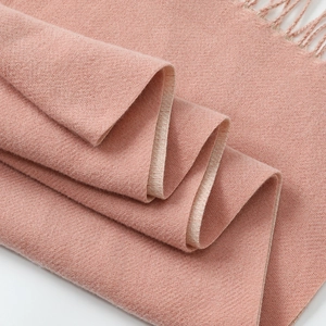 Close-up of pink cashmere blend scarf showing soft knit texture and fringe details