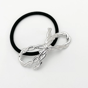 Detail of a black elastic hair tie featuring a polished silver metal knot bow charm