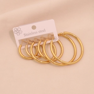 Close-up of three pairs of polished gold stainless steel hoop earrings in different sizes