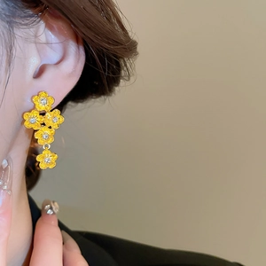 Detail of elegant gold-plated floral drop earrings with sparkling zircon on model ear