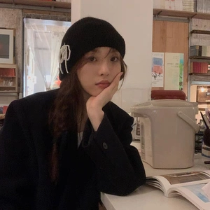 Detail of black knit beanie with pearl bow decoration and elegant warm knit texture