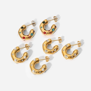 Detail view of hammered C-shaped gold earrings with colorful stones and pearls