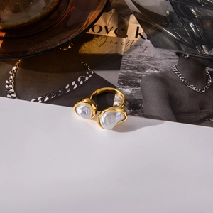 Detail of gold titanium steel open ring with two baroque pearls on a magazine background