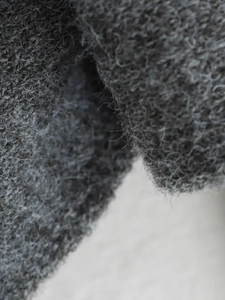 Vista macro del tessuto in misto lana grigio scuro con dettagli in fibra arricciature delle fibre tessili