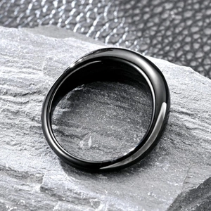 Macro close-up of polished black titanium water drop ring on grey stone texture