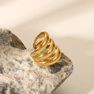 Detail of a multi-layer gold spiral stainless steel ring on a textured natural stone