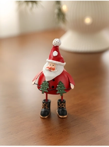Detail shot of a metal Santa Claus figurine holding a wire with miniature green Christmas trees