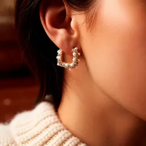 Élégantes boucles d'oreilles en perles plaquées or 18k portées par un mannequin au ton chaud