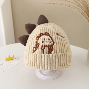 Gros plan sur la maille et la broderie dinosaure d'un bonnet d'hiver beige pour enfant