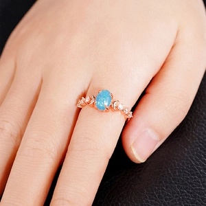 Detail of rose gold ring featuring oval blue opal stone and micro-pave diamonds on band