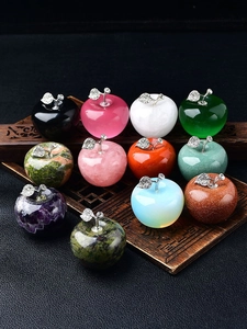 Close-up of apple-shaped gemstones in various colors on a carved wooden tray