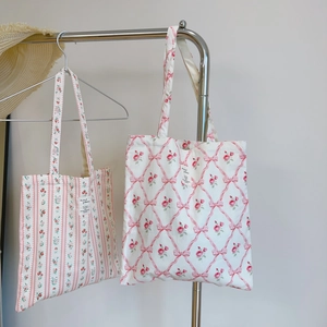 Detail of floral canvas tote bags with ribbon patterns and woven brand labels