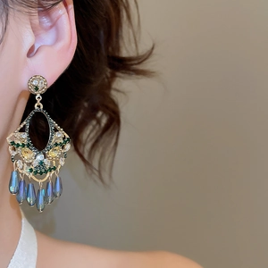 Close-up of vintage tassel earrings with green crystals and blue teardrop beads