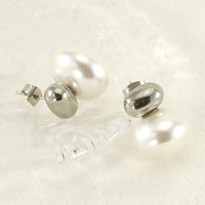 French retro pearl stud earrings in titanium steel shown on textured glass background