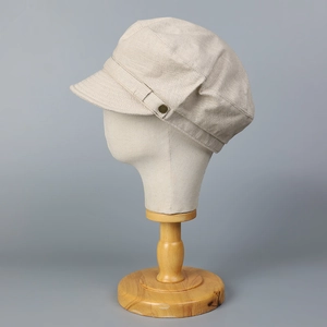 Détail de la casquette en lin montrant le tissu texturé et le bouton rétro en métal