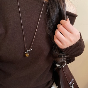 Tiger eye stone pendant necklace with silver accents on a brown knit sweater