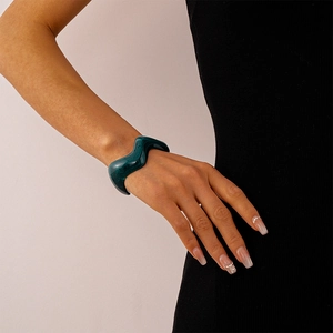 Detail of dark green wavy acrylic bangle on model wrist with minimalist style