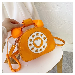 Macro detail of orange vintage telephone handbag featuring creative receiver handle